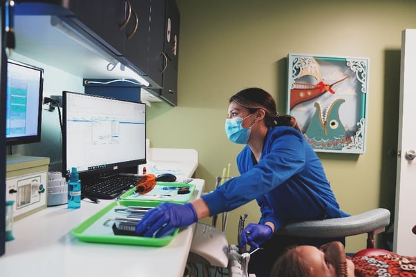 Woman in scrubs at a computer working on dental insurance claim appeals