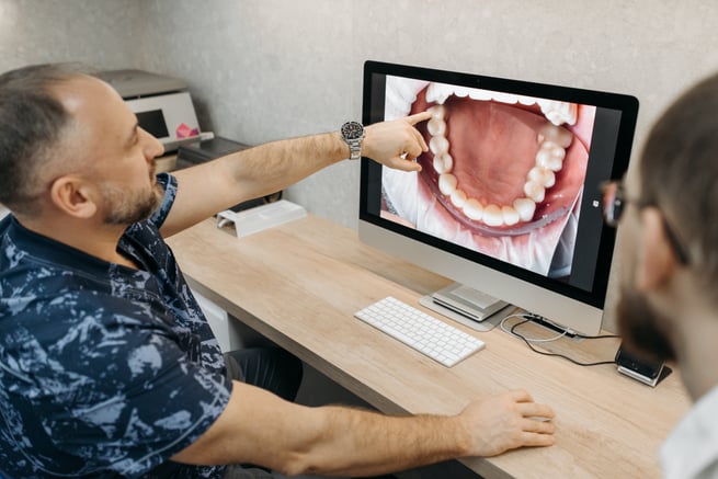 Dentist showing patient an intraoral image of their mouth to attach to an insurance claim